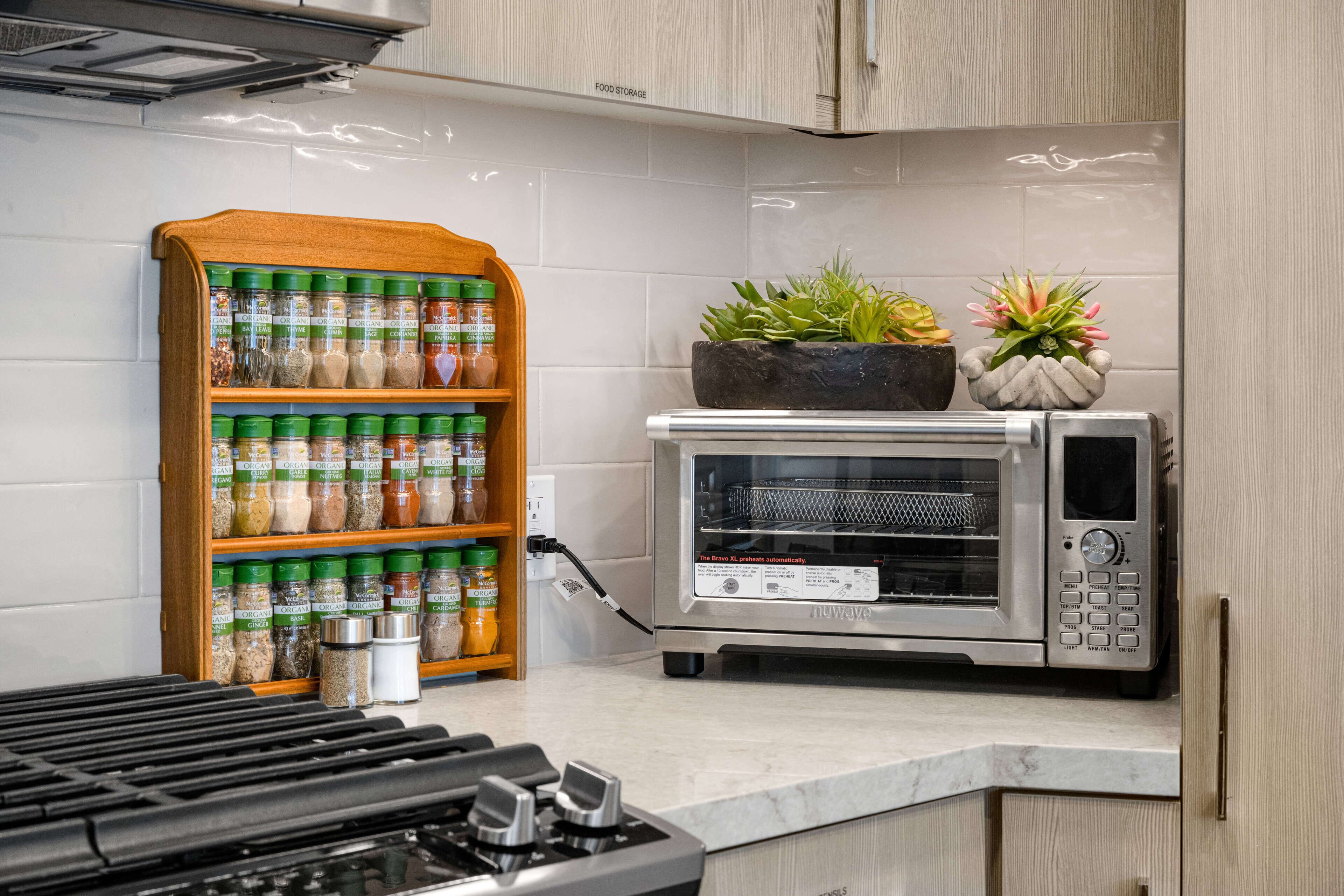 A kitchen with a built-in microwave oven, a spice rack, and a small potted plant on the countertop.