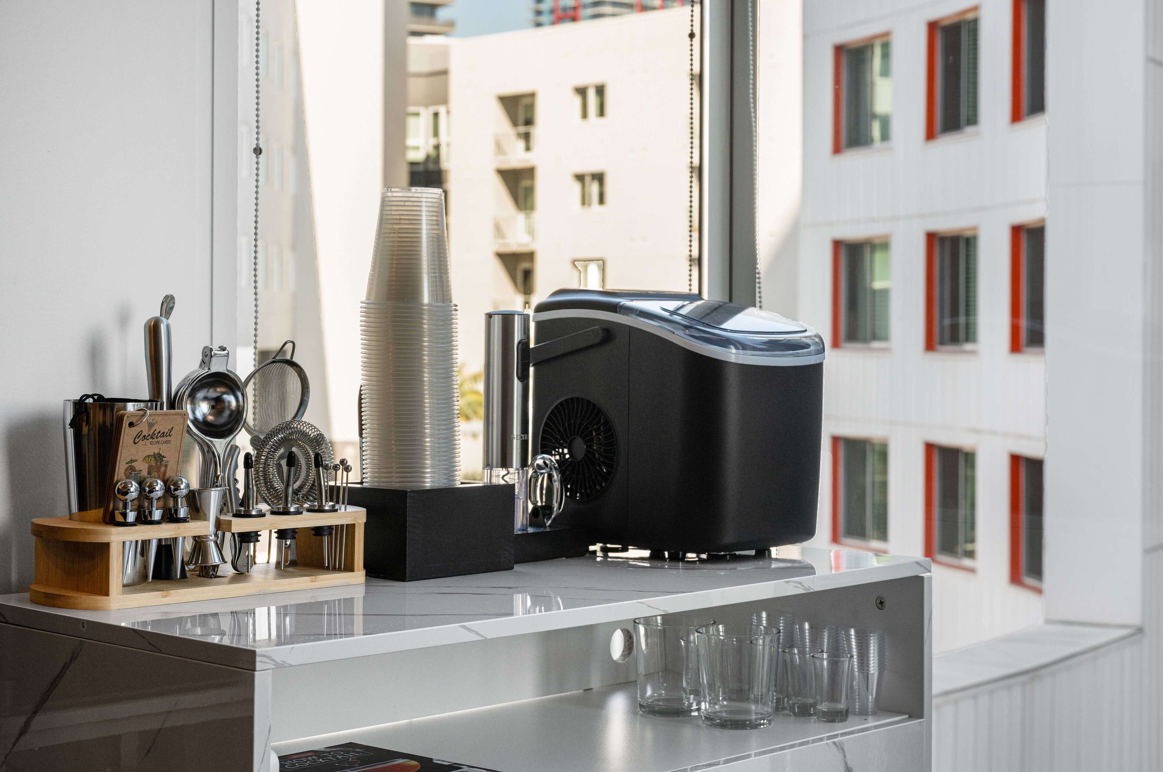Een moderne keuken met een koffieapparaat, een stapel papieren bekers en diverse keukengerei.