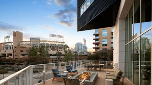 A rooftop terrace with outdoor seating, a fire pit, and a view of surrounding buildings.