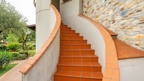 Un escalier en colimaçon avec des marches en terre cuite menant à un mur de pierre.