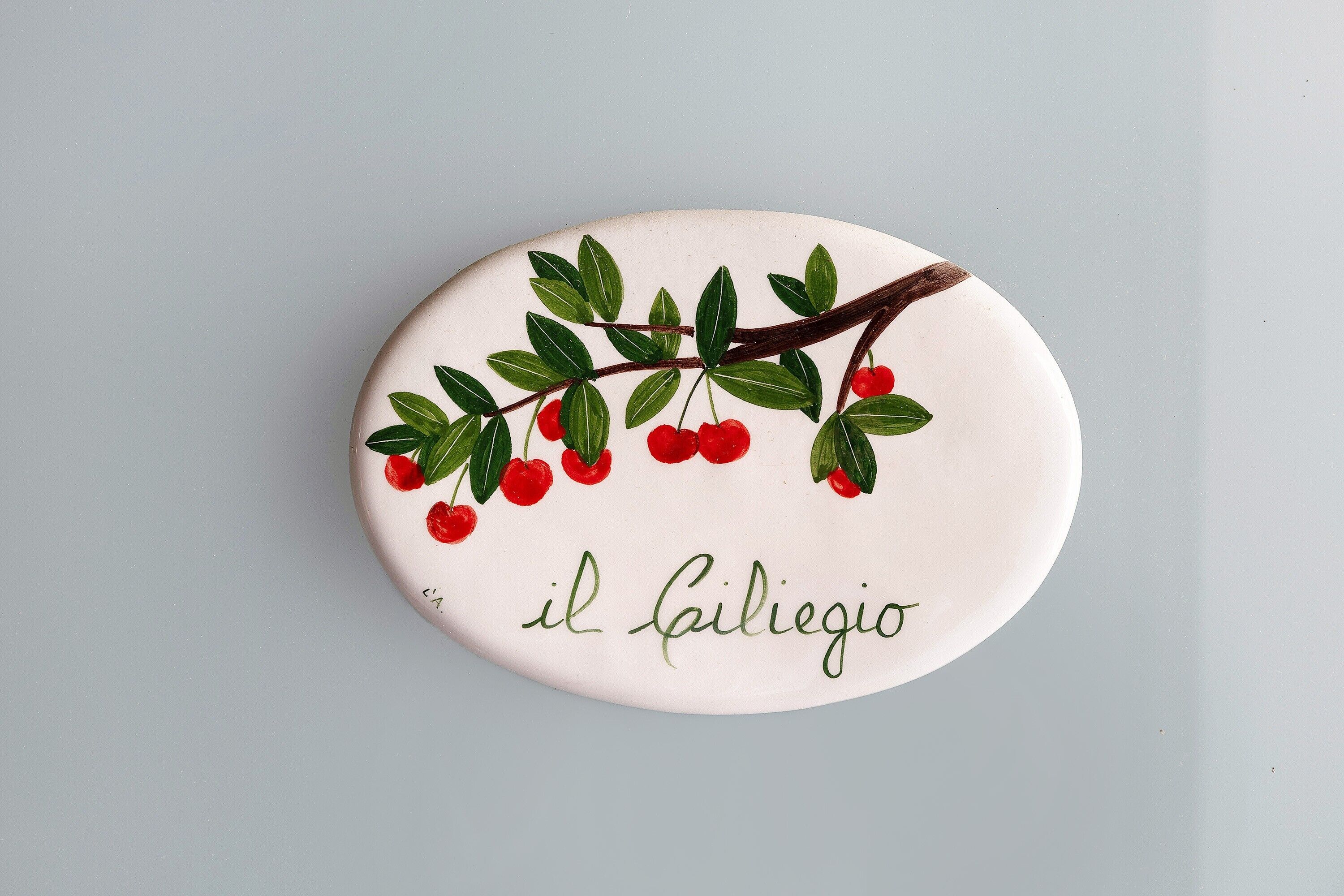 A decorative plate with a branch of red berries and the text 'il Gagliaccio'.