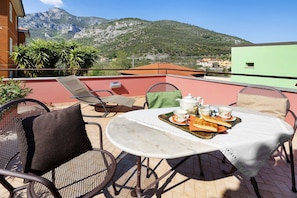 A terrace with a table set for tea, chairs, and a mountain view.