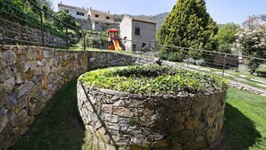Eine steinerne Stützmauer, eine Rasenfläche und ein Spielplatz mit einer Rutsche.