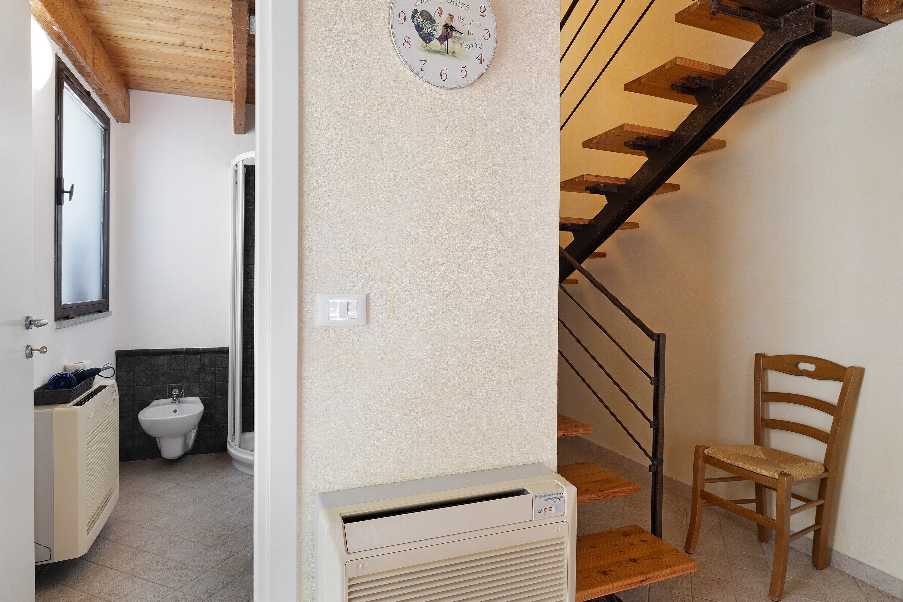 Une salle de bain équipée d’un bidet, d’un radiateur et d’une horloge murale.