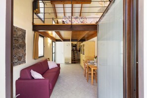 A compact living space with a sofa, dining table, and a staircase leading to an upper level.