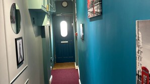 A hallway with teal walls, a red carpet, and a blue door at the end. - Guest&Rest Hotel (London)