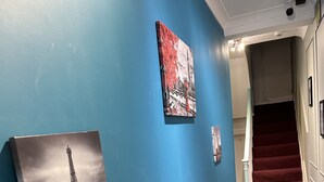 A hallway with a blue wall, a red carpet, and a staircase leading to an upper floor. - Guest&Rest Hotel (London)
