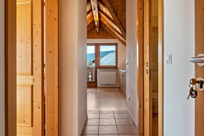 Un couloir intérieur en bois mène à une salle de bain offrant une vue sur les montagnes.