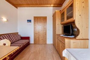 Un intérieur en bois comprenant un canapé, une table, un téléviseur et des meubles de rangement en bois.