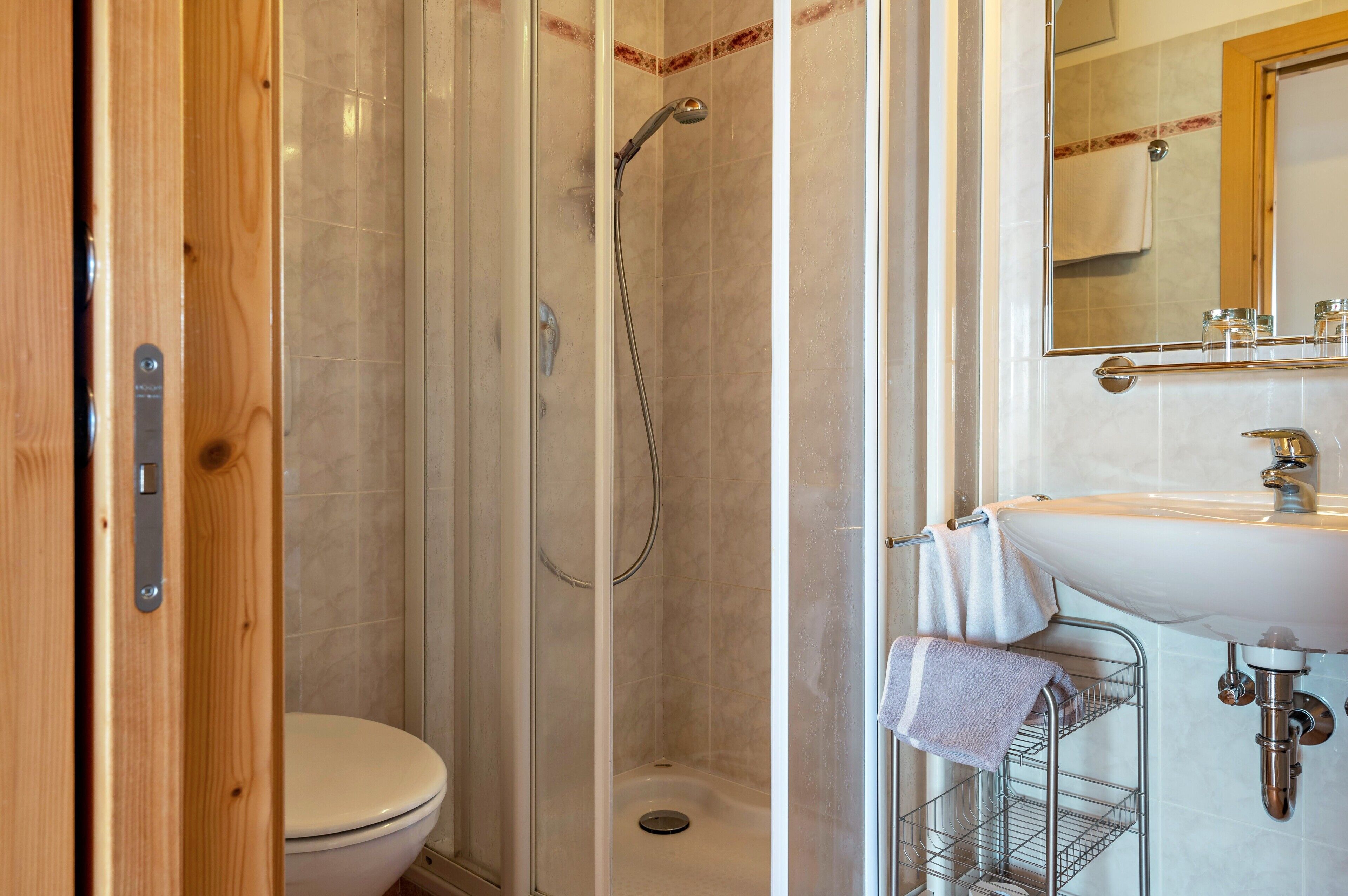 Een badkamer met een douche, toilet, wastafel en een spiegel.