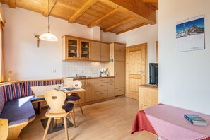 A cozy kitchen with wooden cabinets, a dining area with a bench, and a television.