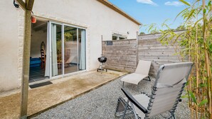 A patio with a chair, a barbecue grill, and a wooden fence.