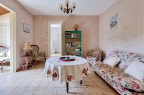 Una habitación con una mesa redonda, un sofá, una estantería y una silla.