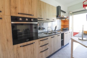 Une cuisine moderne avec des meubles en bois, une cuisinière noire et un évier en acier inoxydable.