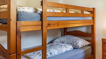 Ein Etagenbett mit Holzrahmen, das untere Bett mit einer blumengemusterten Matratze und das obere Bett mit einer schlichten Matratze.