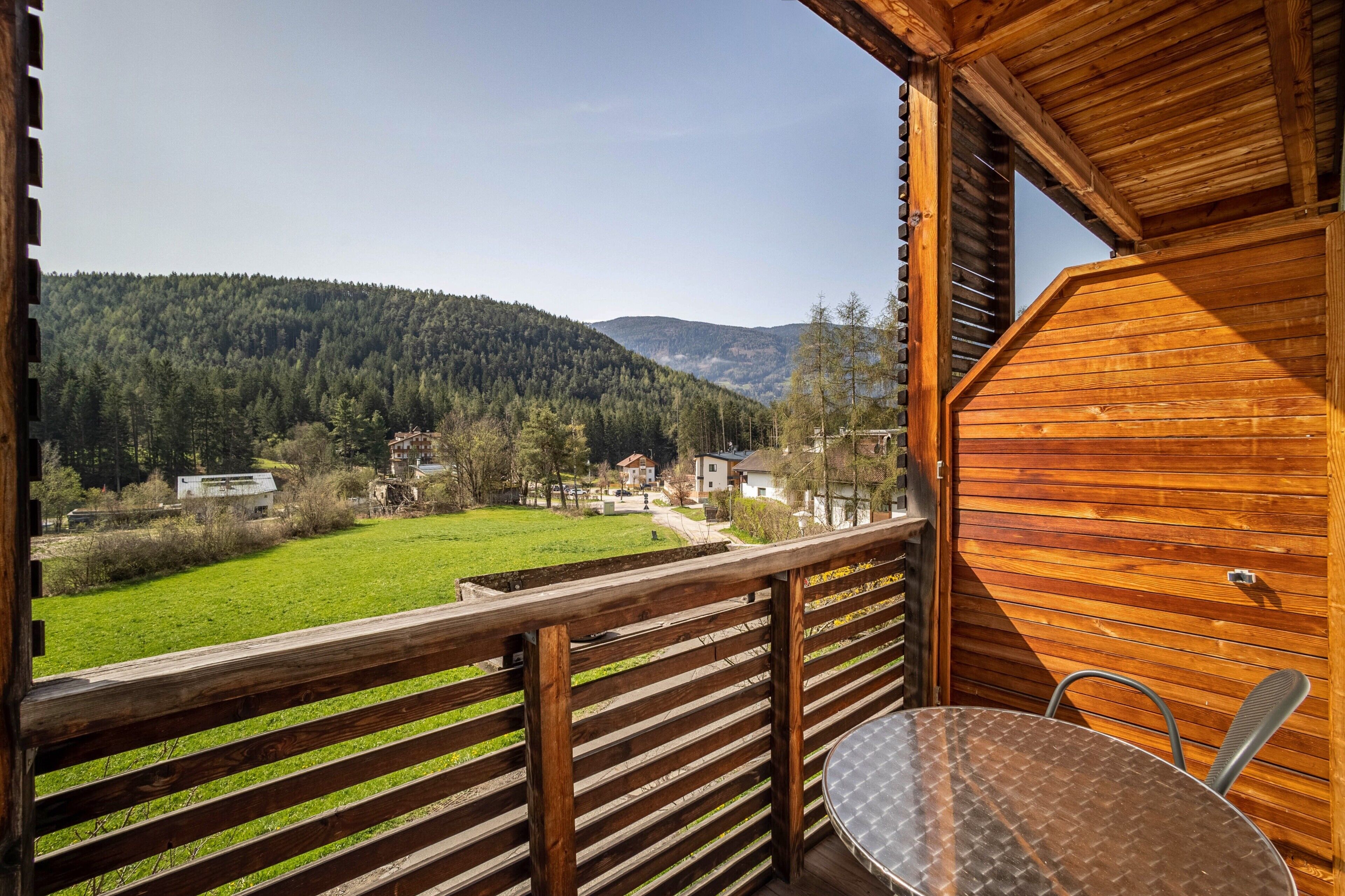 Eine Holzhütte mit Balkon, Tisch und Stuhl.
