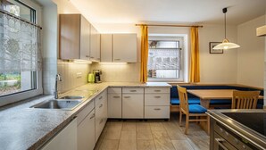 A compact kitchen with a sink, stove, and dining area with chairs.