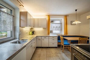 Une cuisine compacte équipée d’un évier, d’une cuisinière et d’un coin repas avec des chaises.