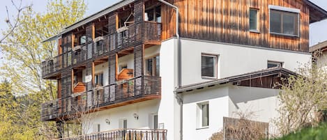 Ein zweistöckiges Gebäude mit Balkonen, einem Steinsockel und einem Holzaufbau.