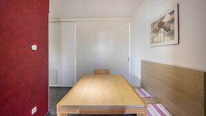 Una habitación con una mesa de madera, una cama con cabecero de madera, una pared roja y un cuadro enmarcado en la pared.