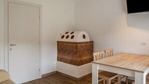Ein Zimmer mit einem Holzkasten, einer weißen Tür, einem Holztisch und einem an der Wand montierten Fernseher.