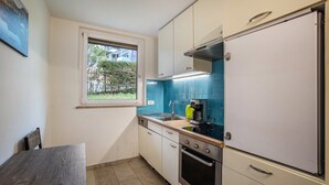 Eine kleine Küche mit Fenster, Spüle, Kaffeemaschine und Herd.