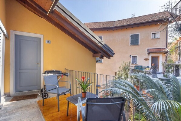 A balcony with a grill, a door, and a small table with chairs.