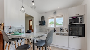 A modern kitchen with a dining area, featuring a granite countertop, a microwave, a stove, and a sink.