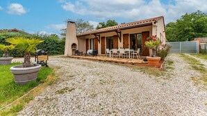 A house with a patio, outdoor seating, and a garden.