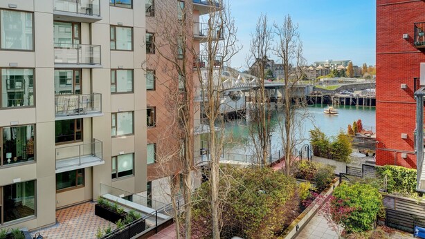A modern apartment building with balconies overlooking a river.