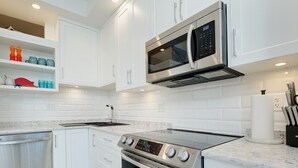 A modern kitchen with white cabinetry, a stainless steel oven, a microwave, and a built-in dishwasher.
