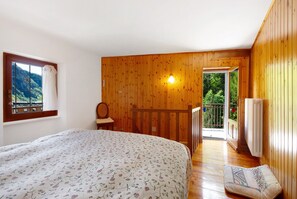 A bedroom with a bed, a window, a wooden wall, a chair, and a balcony. - Holiday Home 'Casa Savin 35' with Mountain View, Private Garden and Balcony (Pontboset)