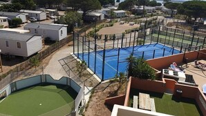 A residential area with multiple houses, a tennis court, and a swimming pool. - Mobile Home 'Mobil-home Camping Mar Estang' with Lake View, Shared Pool & Air Conditioning (Canet-en-Roussillon)