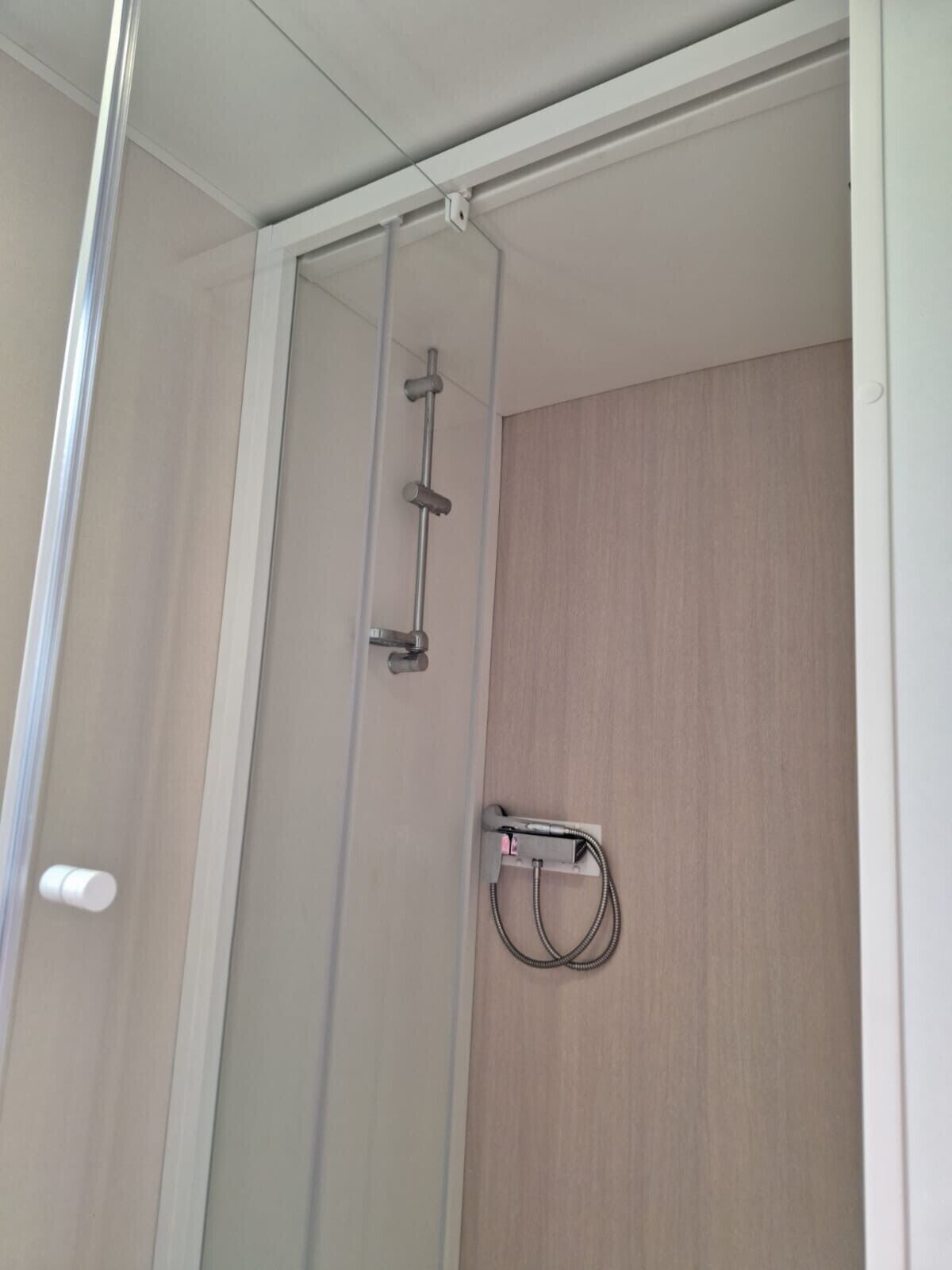 Eine Dusche mit Glastür, einem Handtuchhalter und einem wandmontierten Handtuchspender.