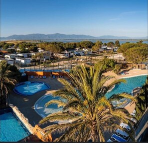 Ett semesterparadis med flera pooler, palmer och utsikt över avlägsna berg.