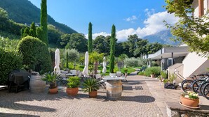Ein Innenhof mit Sitzgelegenheiten im Freien, Blumentöpfen und einem Blick auf die Berge.