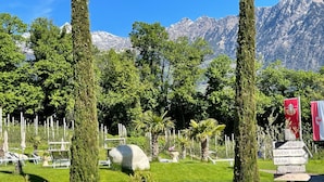 Un jardin agrémenté d’un panneau d’accueil, de chaises longues et offrant une vue sur les montagnes.