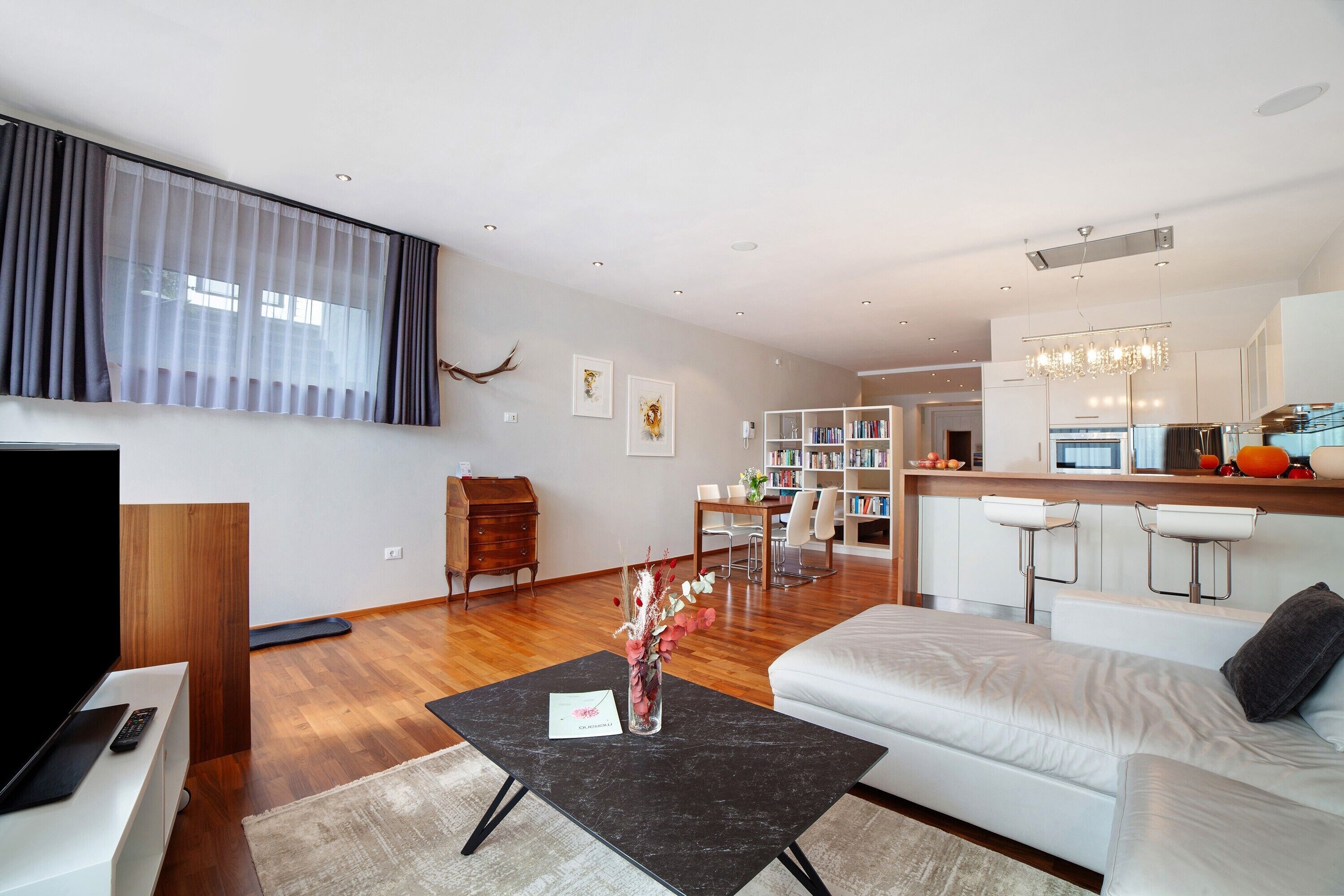 Un salon moderne comprenant un canapé, une table basse, un téléviseur et un coin repas avec des chaises et une table.