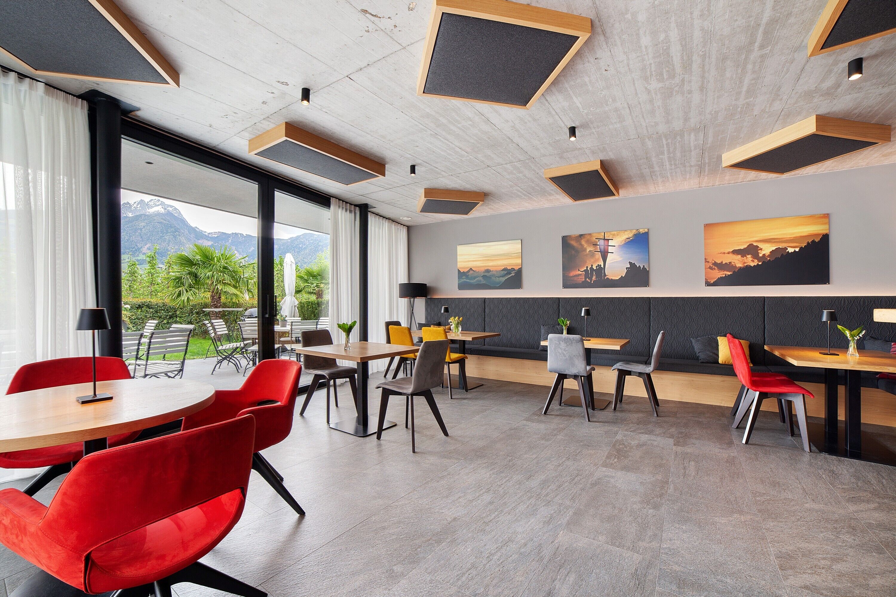 A modern dining area with tables and chairs, large windows, and artwork on the walls.