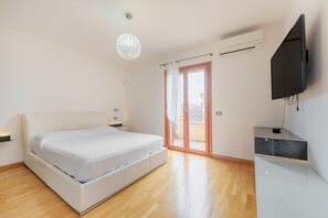 A modern bedroom with a bed, a TV, and a sliding glass door to a balcony.