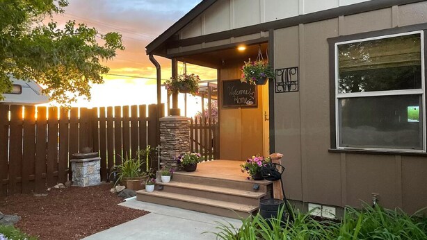 A building with a wooden fence, a stone planter, and a welcome sign.