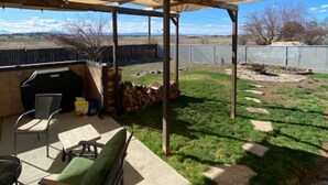 A covered patio area with a grill, outdoor seating, and a view of the surrounding landscape.