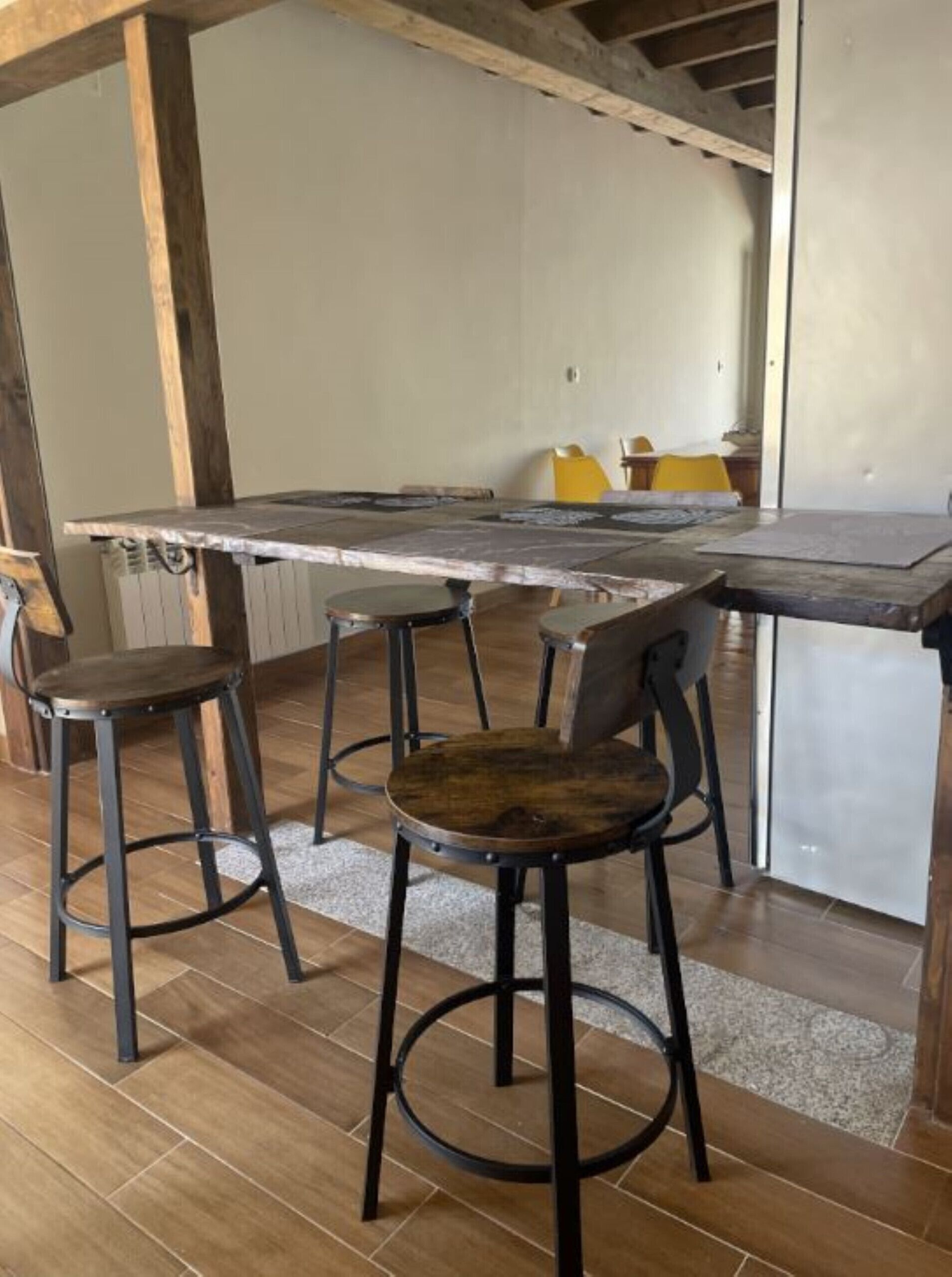 Une cuisine rustique avec une grande table en bois et quatre tabourets.