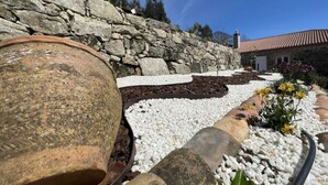 A garden with a stone wall, white pebbles, and yellow flowers. - YourHouse A Casa Da Corona, beautiful country house (Ourense)