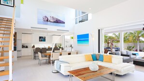 Un vaste espace de vie comprenant un canapé blanc, une table basse en bois et un coin repas avec des chaises et une table.