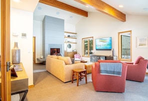 A spacious living room with a fireplace, a television, and a view of the outdoors through large windows.