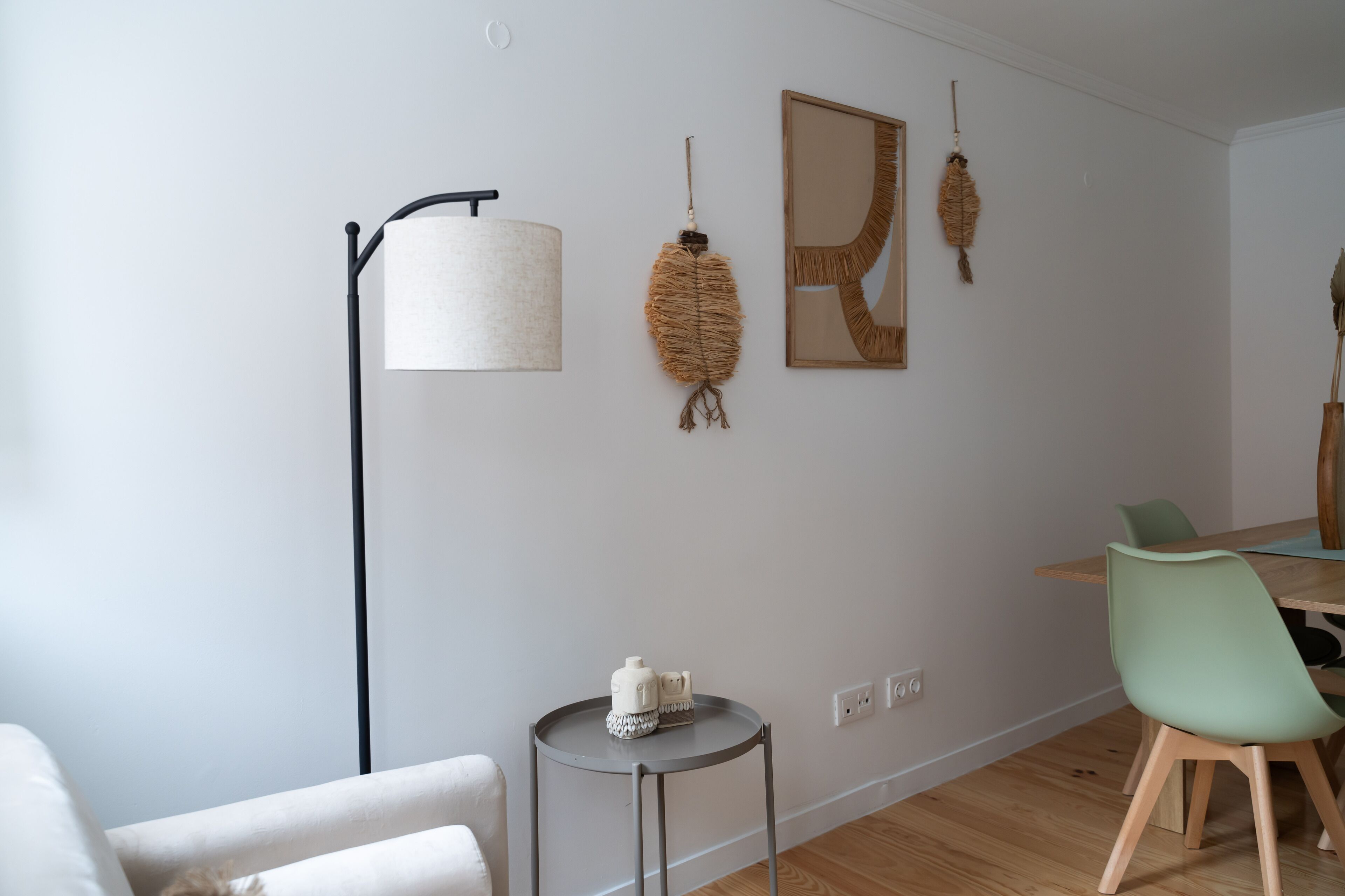 A modern living room with a round table, a green chair, a floor lamp, and wall-mounted decor.
