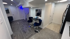 Una cucina moderna con pavimento in legno scuro, un piano di lavoro nero e un'area pranzo con due sedie blu.