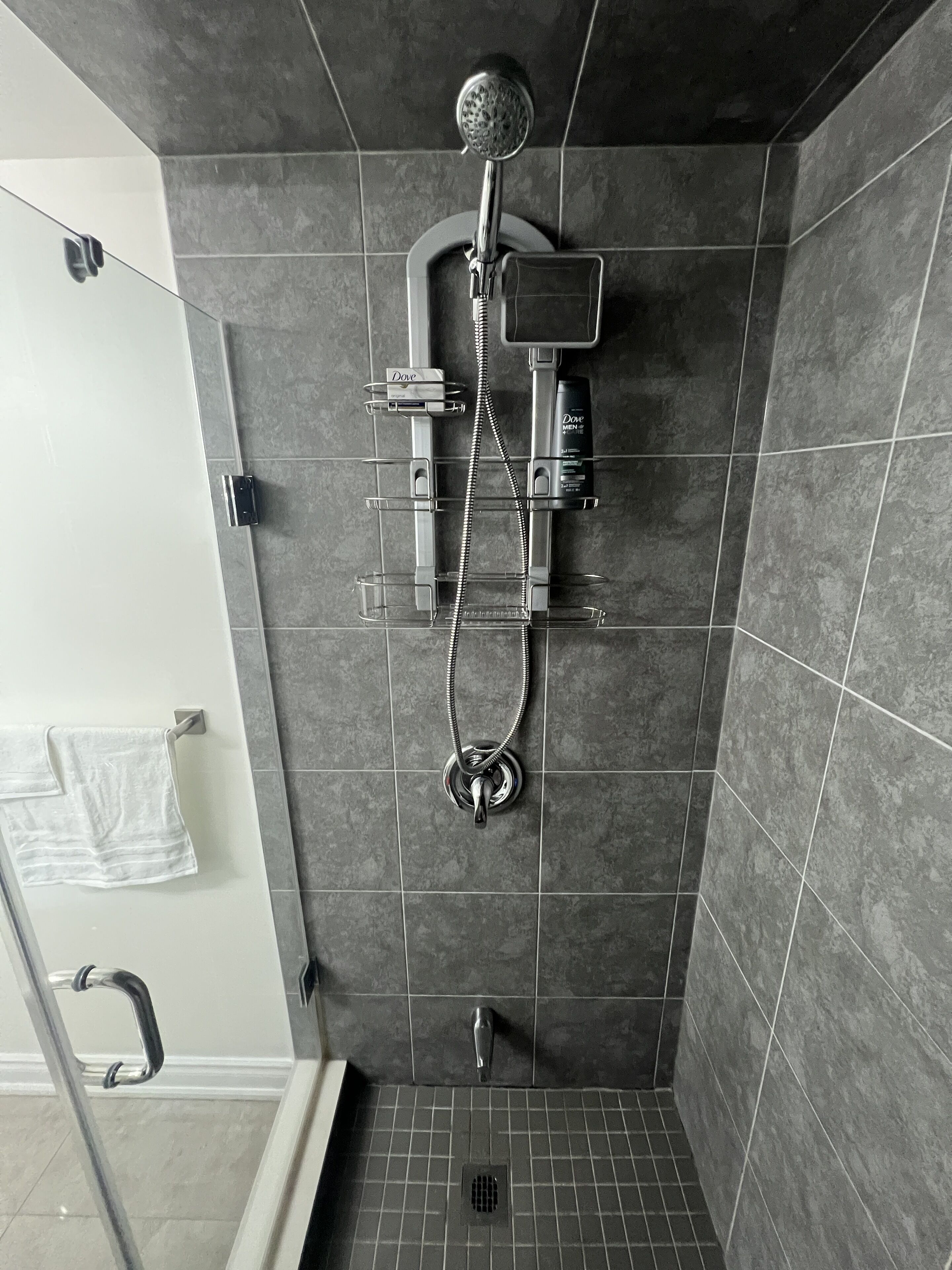 A shower with a handheld showerhead, a handheld shower attachment, and a wall-mounted showerhead.