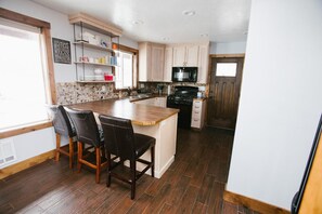 Una cocina con isla central, armarios de madera, microondas y estufa.